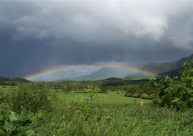 Paisaje del Valle de Mena con vistas de La Peña y praderías en plena tormenta con arcoiris.
